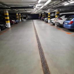 Robik , Sylwia Stępień - Wnętrze parkingu podziemnego po umyciu posadzki, widoczny odpływ liniowy na środku i czyste, betonowe podłoże.