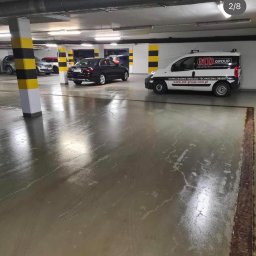 Robik , Sylwia Stępień - Błyszcząca, mokra posadzka parkingu podziemnego po umyciu, z widocznym samochodem osobowym i vanem firmy sprzątającej MD Group.