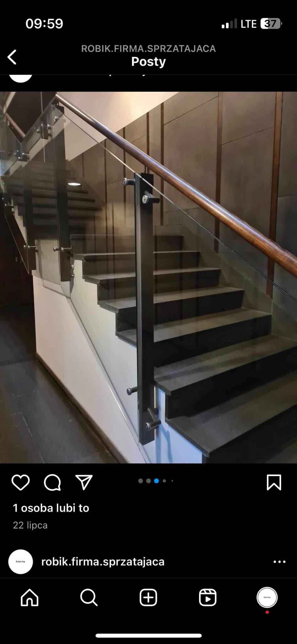 Nowoczesne schody z ciemnymi stopniami, szklaną balustradą i drewnianą poręczą, prezentowane w pomieszczeniu z szarymi panelami ściennymi.