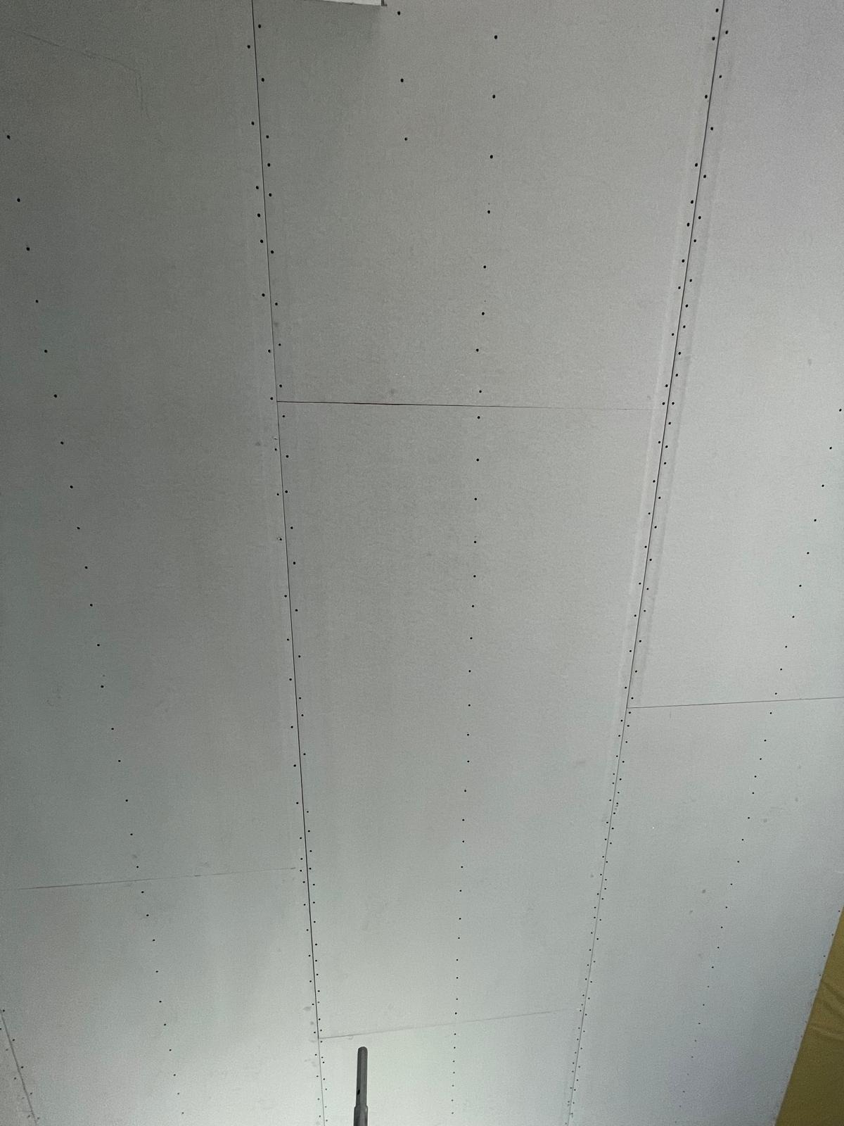 Szare płyty gipsowo-kartonowe zamocowane do sufitu, widoczne wkręty wzdłuż krawędzi płyt.