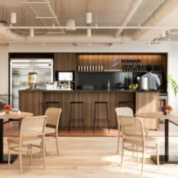 Jasne wnętrze biura rachunkowego z drewnianymi meblami, barem kawowym i logo firmy Sonari na ścianie. W tle widoczny pracownik przy ekspresie do kawy.