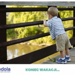 Chłopiec w paski i beżowych spodenkach opiera się o metalową barierkę mostu, obserwując rzekę. Na drewnianej podłodze mostu leżą zielone gałązki i pojedynczy liść.