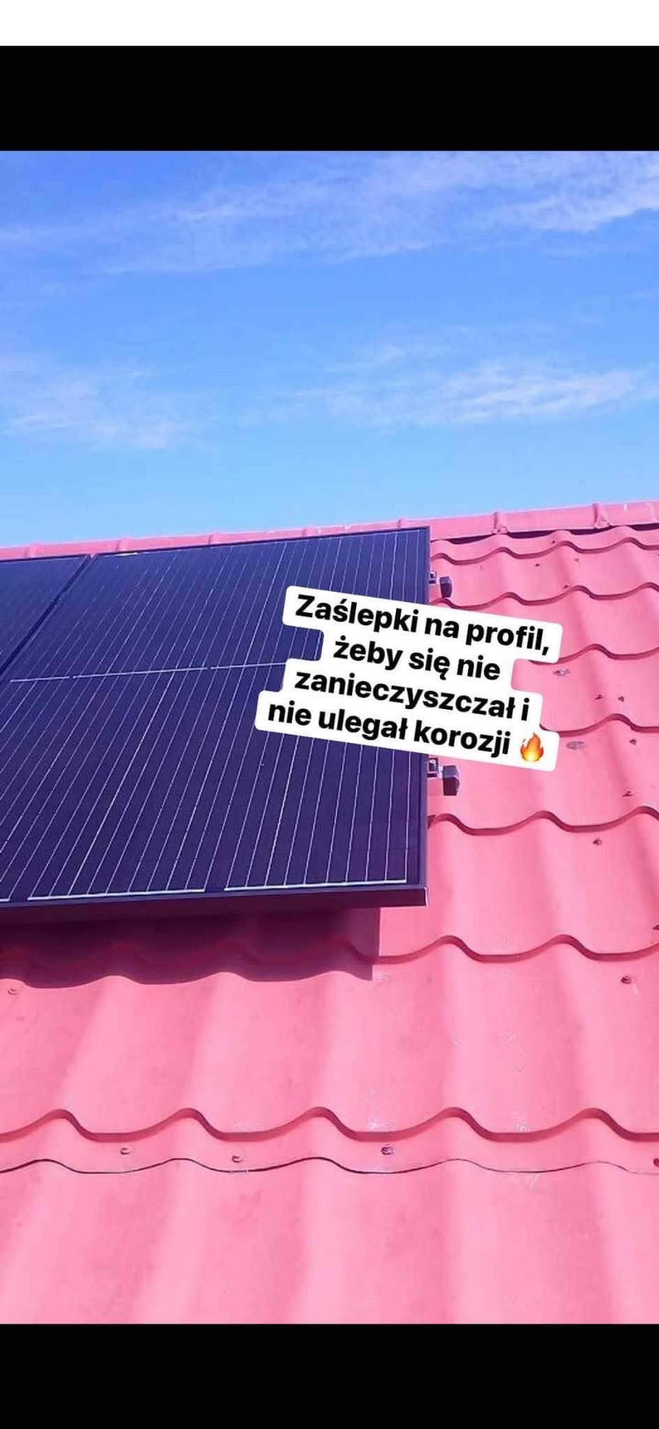 Panele fotowoltaiczne zamontowane na różowym dachu z blachodachówki, widok na niebieskie niebo. Na zdjęciu tekst 'Zaślepki na profil, żeby się nie zanieczyszczał i nie ulegał korozji'.