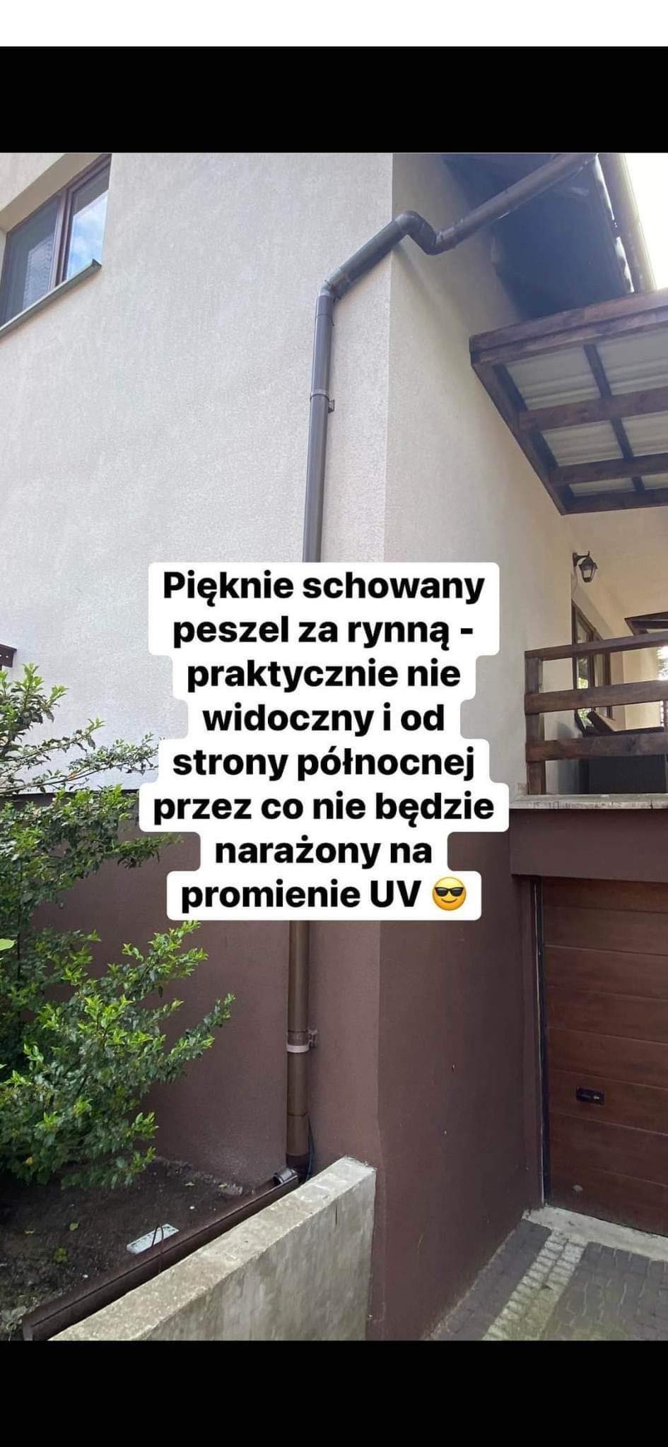 Brązowa rynna spustowa na elewacji domu, z ukrytym peszelem od strony północnej, zabezpieczającym przed promieniami UV.