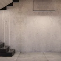 Minimalistyczne wnętrze domu z betonową ścianą, schodami z ciemnego drewna z podświetleniem pionowym i wiszącą lampą liniową.