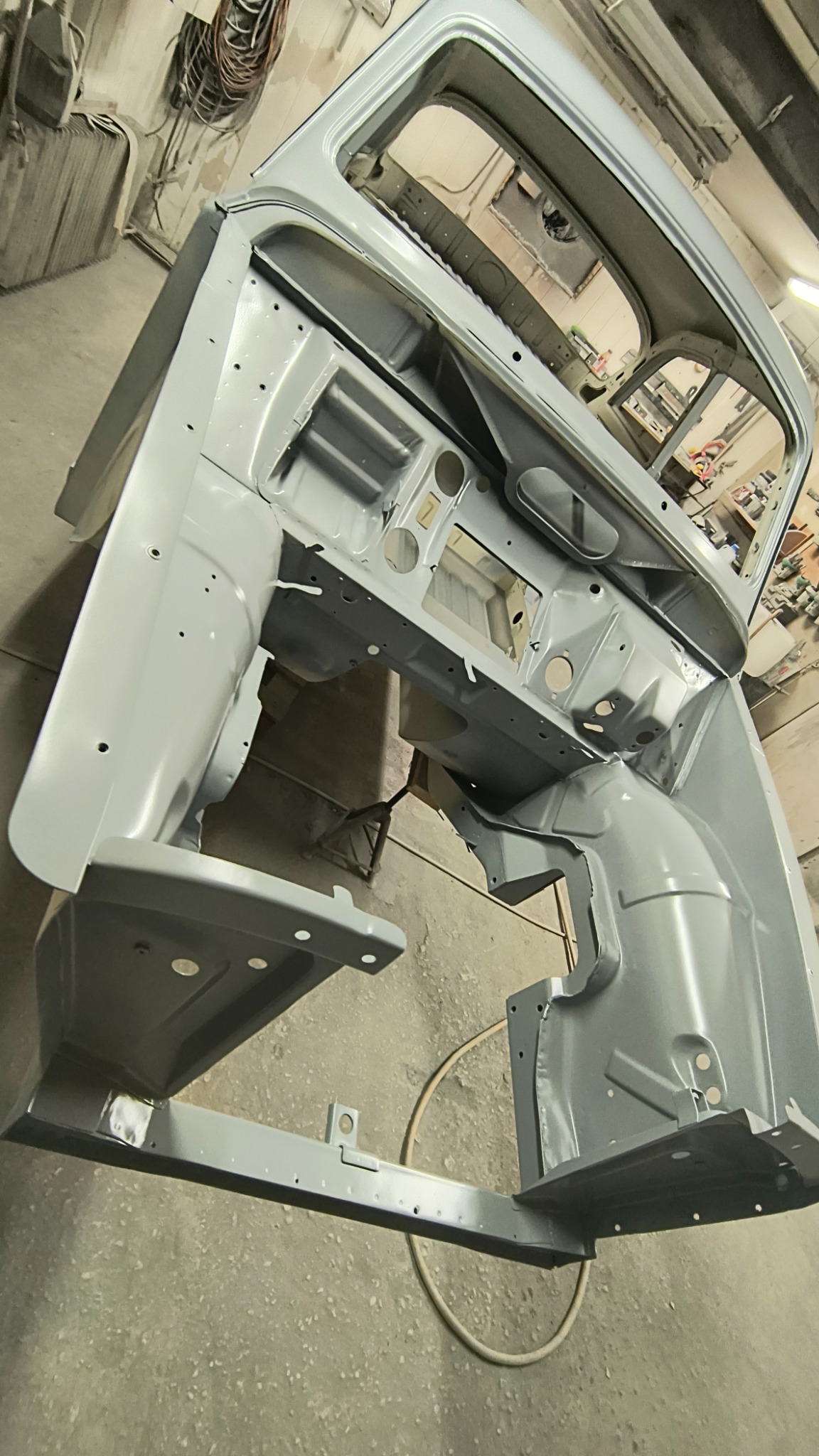 Surowa karoseria samochodu po wstępnym malowaniu, widoczne spawy i przygotowanie do dalszych prac lakierniczych.