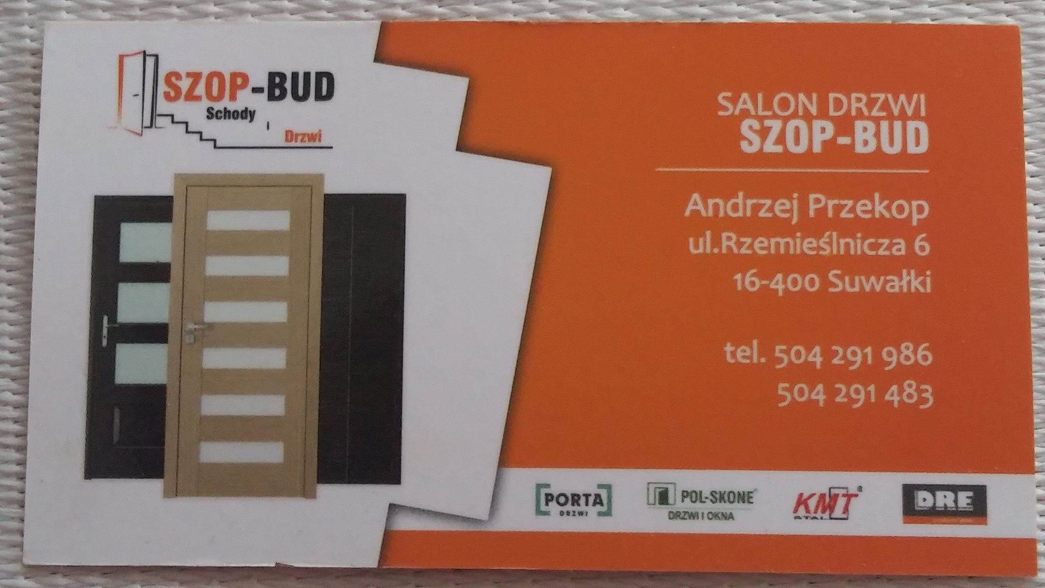 Wizytówka firmy z salonem drzwi, przedstawiająca logo firmy Szop-Bud, adres, telefon oraz przykładowe modele drzwi w kolorach ciemny brąz i jasne drewno.