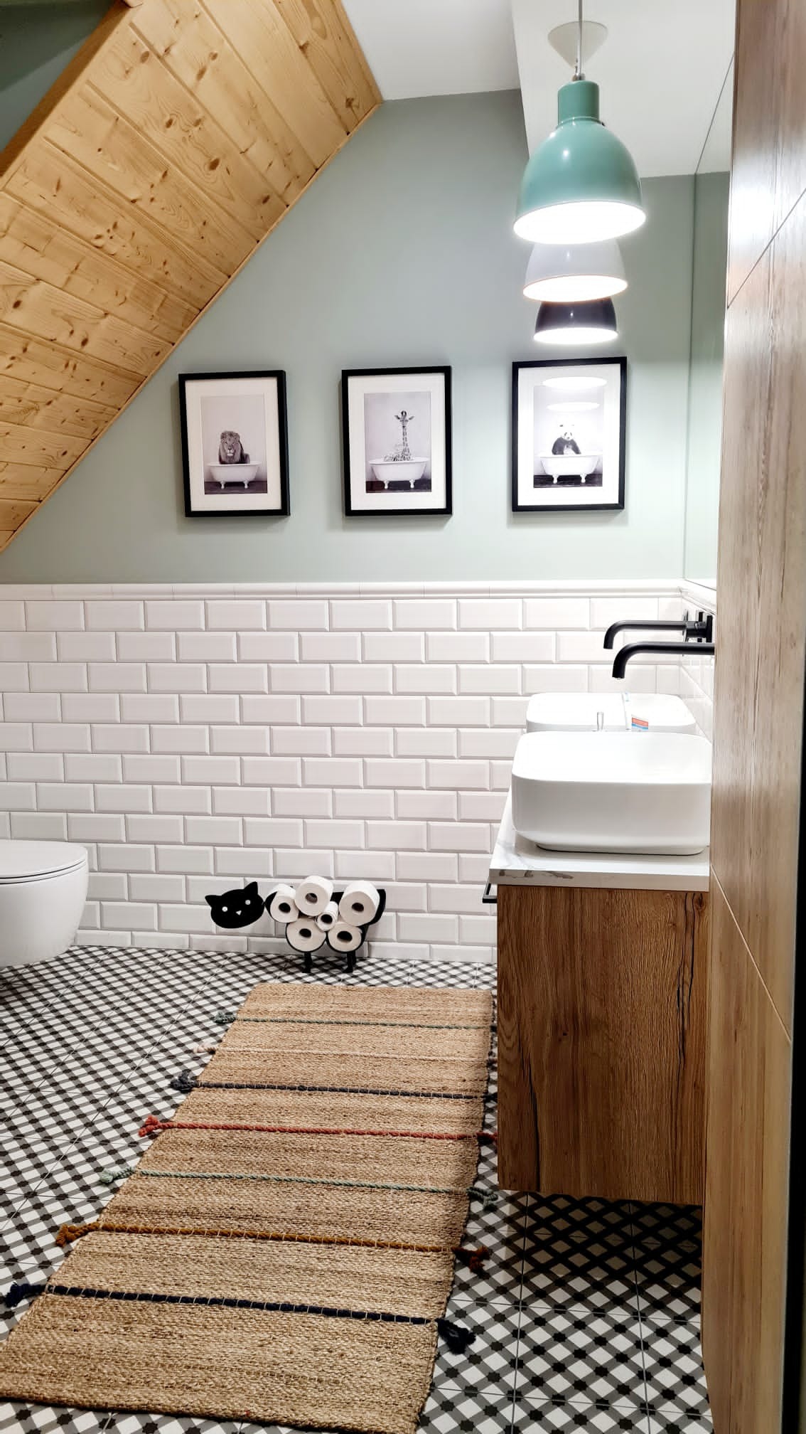Nowoczesna łazienka na poddaszu z drewnianą boazerią, białą glazurą typu metro, podwójną umywalką nablatową, czarno-białą podłogą w kratkę i dywanikiem z juty z kolorowymi paskami, dekorowana...