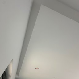 MR. WHITE Marek Ryborz - Białe, gładkie wykończenie sufitu pod skosem, z widocznymi otworami na oświetlenie. Minimalistyczny design, świeżo po remoncie. Widok z dołu.