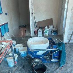 YEVHENII SEMENOV - Agregat malarski Pagat T-Max wypełniony masą szpachlową, wiaderka z masą Semina oraz worki ze szpachlą w surowym wnętrzu w trakcie prac wykończeniowych.