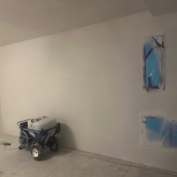 YEVHENII SEMENOV - Pokój w trakcie malowania natryskowego, z zakrytymi folią otworami wentylacyjnymi i maszyną do malowania natryskowego na podłodze.