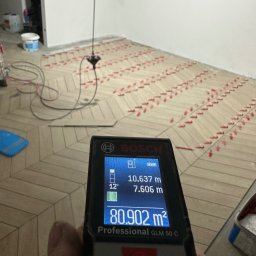YEVHENII SEMENOV - Pomiar powierzchni parkietu ułożonego w jodełkę, wykonany laserowym miernikiem odległości Bosch GLM 50 C, z widocznymi krzyżykami dystansowymi.