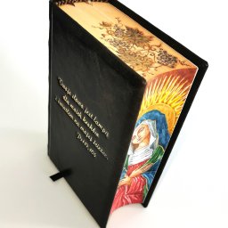 Biblia w małym formacie, z ręcznie malowanymi brzegami i obrazem Matki Bożej, z dedykacją na okładce będącą fragmentem Psalmu 119, 105. Wyjątkowy prezent z okazji Święceń Kapłańskich.