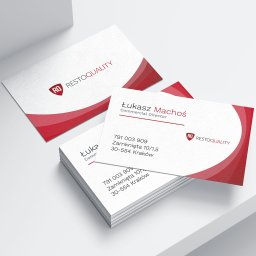 Arteon - Stos wizytówek z logo i danymi kontaktowymi 'Restoquality', jedna wizytówka leży obok, całość na białym tle,  minimalistyczny design z czerwonym akcentem.
