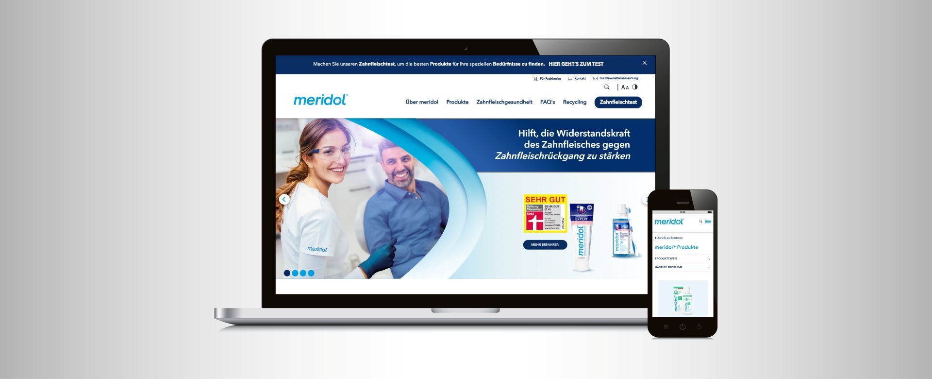 Laptop i smartfon wyświetlają stronę internetową Meridol z uśmiechniętymi dentystami i produktami do higieny jamy ustnej. Strona w języku niemieckim.