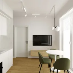 Wnętrze mieszkania: biała kuchnia z marmurowym backsplashiem, indukcyjna płyta grzewcza, biały okrągły stół z trzema zielonymi krzesłami, telewizor na ścianie, drewniana podłoga, oświetlenie...