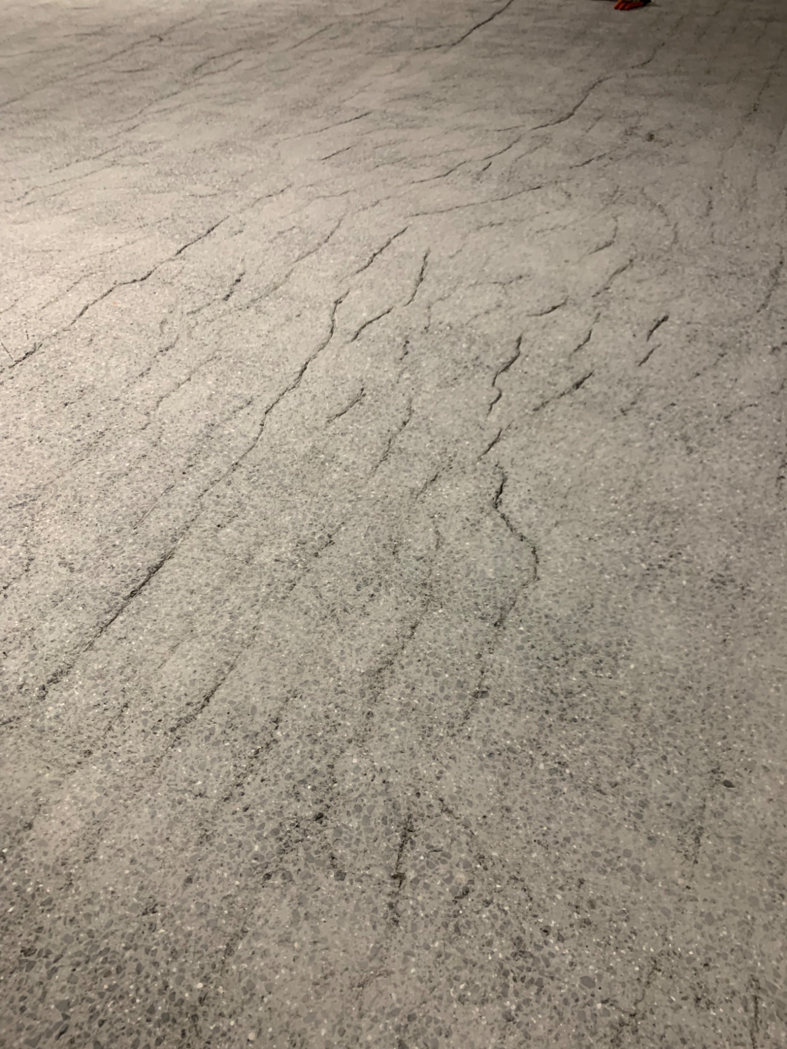 Szara posadzka z widocznymi delikatnymi spękaniami, przypominająca naturalny kamień, o matowym wykończeniu.