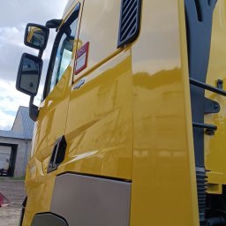 AUTO-DETAILING KAMIL KNOP - Żółta kabina ciężarówki Renault Trucks po renowacji, widoczna z dołu pod kątem. Błyszcząca powierzchnia odbija niebo.