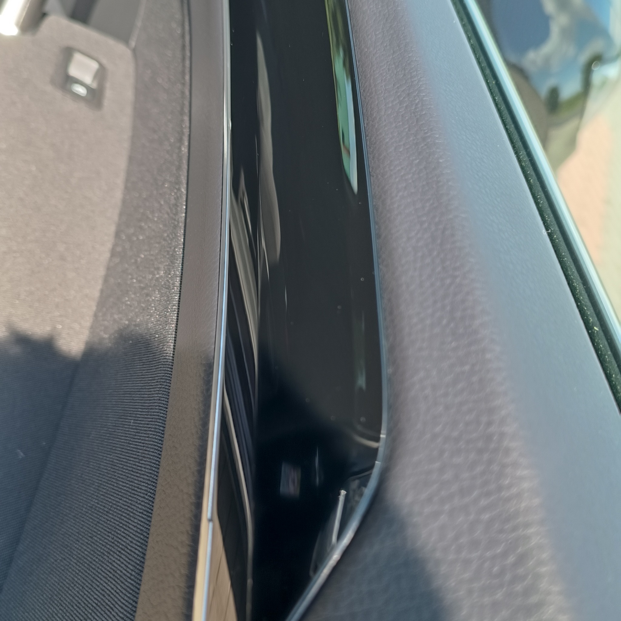 Wnętrze samochodu: czarna tapicerka drzwi z widocznym schowkiem i fragmentem fotela z szarej tkaniny. Widoczne detale wykończenia wnętrza.