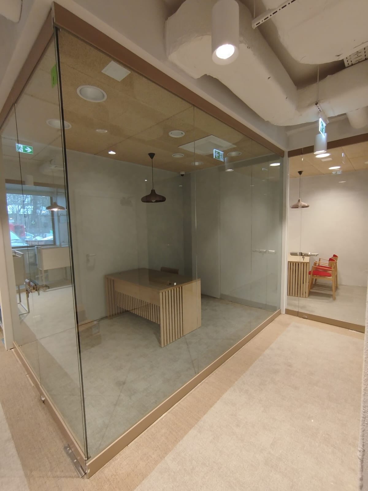 Szklane ścianki działowe w biurze w Brzesku. Przezroczyste szkło oddziela przestrzeń, widoczny stół i krzesła. Nowoczesny design, jasne wnętrze.