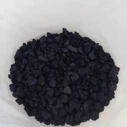 Kupa błyszczącego, czarnego opału w przezroczystym worku, widoczne nieregularne kształty bryłek i odbicia światła.