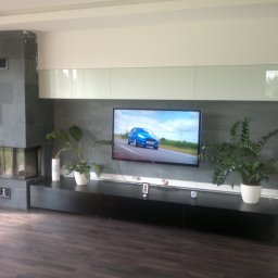 M INSTAL s.c. Monika Woźniak, Sebastian Woźniak - Kominek narożny z giętą szybą podnoszoną do góry. Obudowa obłożona grafitowym łupkiem kamiennym.