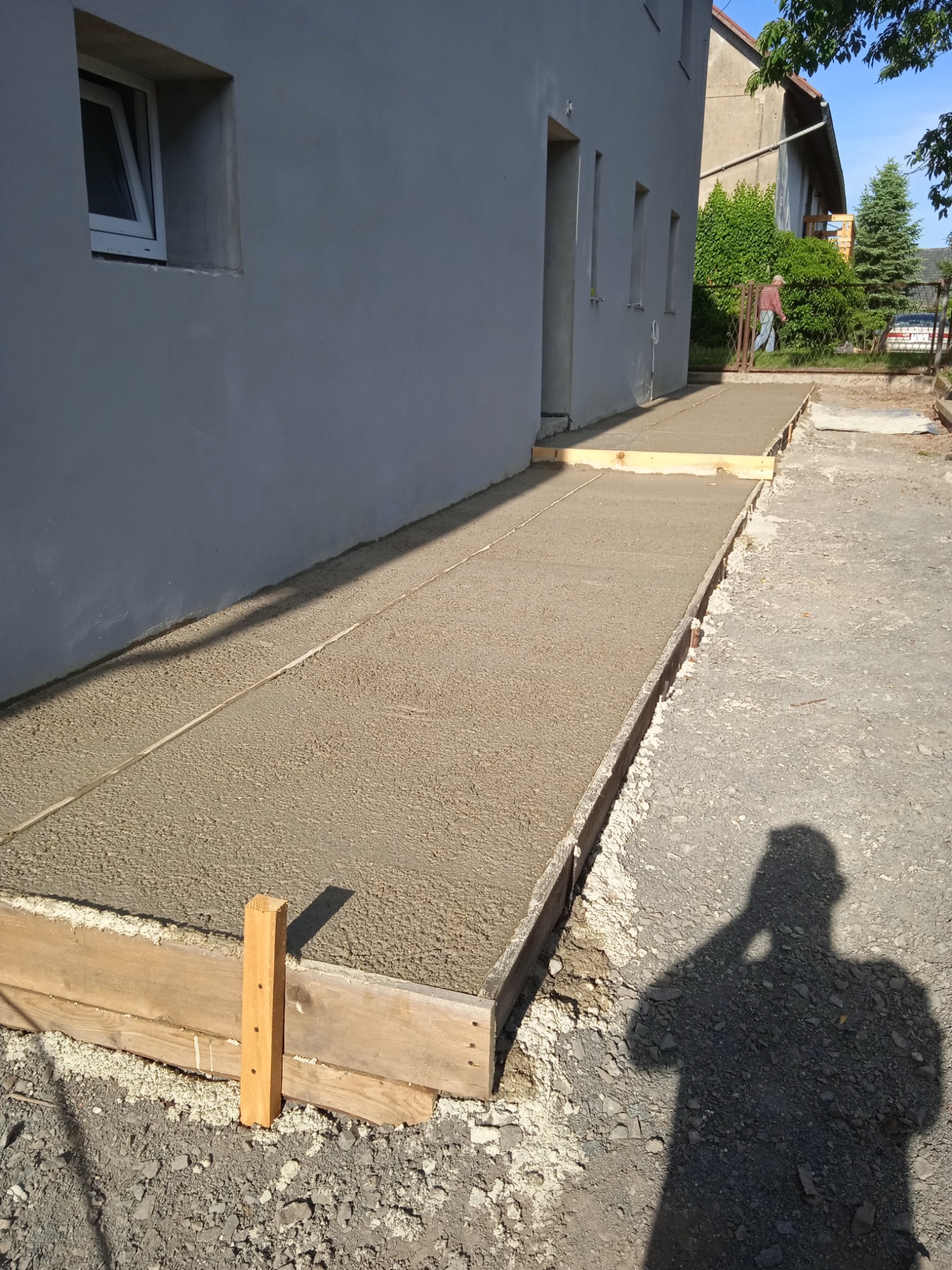 Wylewka betonowa na zewnątrz budynku w drewnianym szalunku, widoczny cień osoby fotografującej.