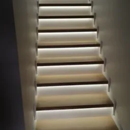 Nowoczesne schody z podświetleniem LED, widok z dołu, minimalistyczny design, jasne drewno i białe wykończenie.