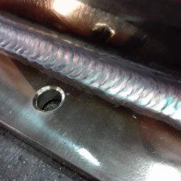 MARZOS Agnieszka Gołąb - Szlifowana powierzchnia metalowa z precyzyjnym spoinem, widoczny otwór montażowy, detale obróbki.