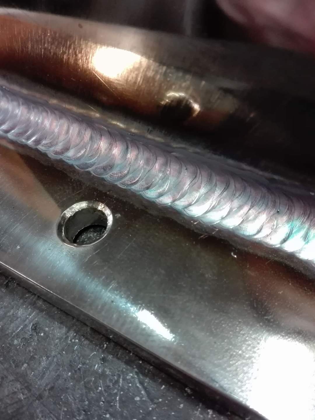 Szlifowana powierzchnia metalowa z precyzyjnym spoinem, widoczny otwór montażowy, detale obróbki.