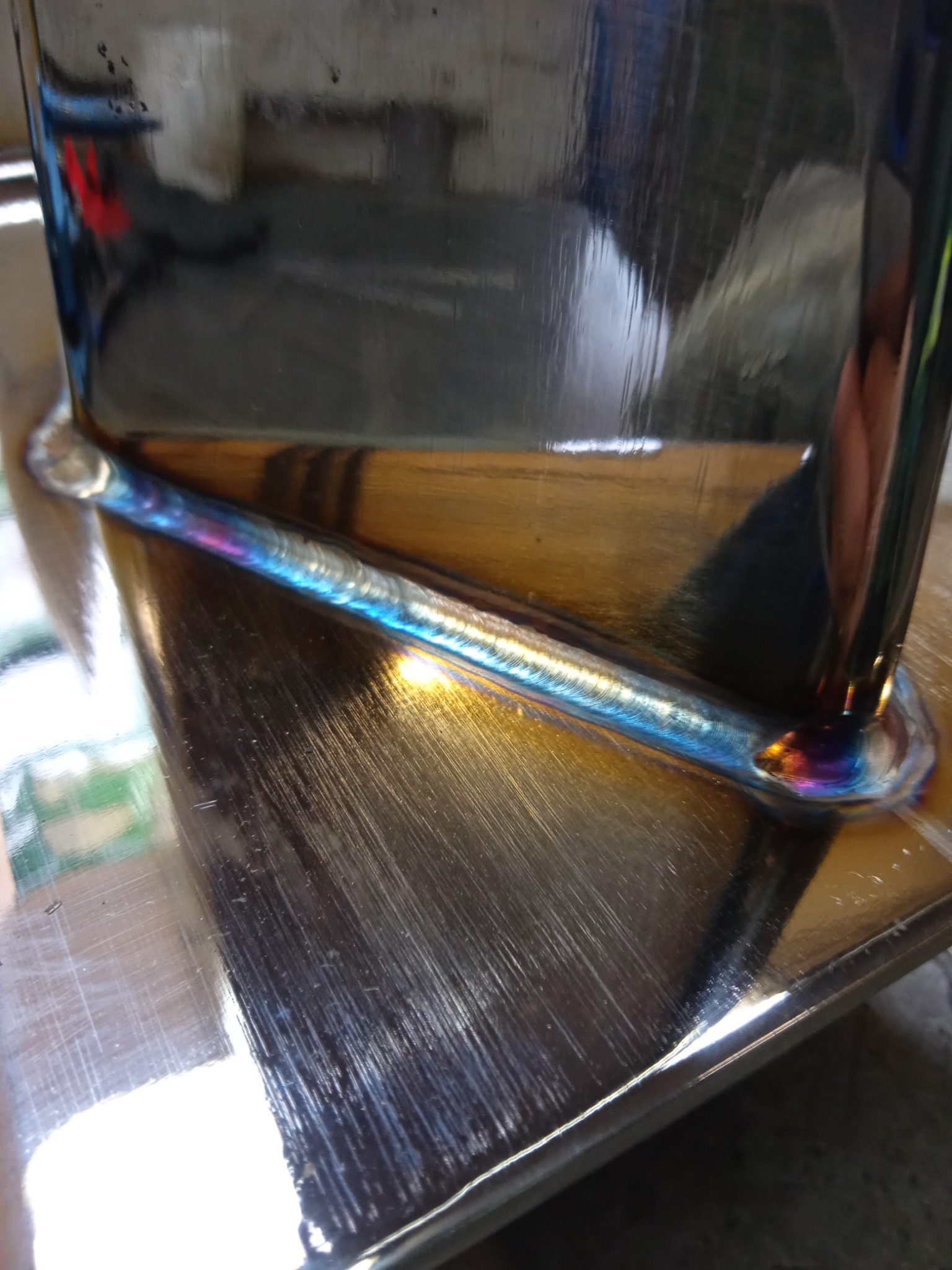 Spoina TIG na stali nierdzewnej, widoczne tęczowe przebarwienia termiczne, wysoki połysk metalu.