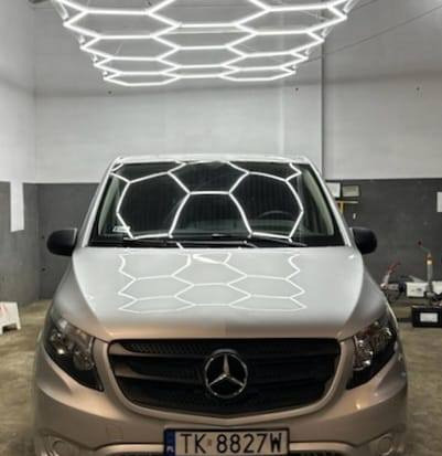 Srebrny Mercedes V-klasy pod heksagonalnym oświetleniem LED w warsztacie, widoczna tablica rejestracyjna TK 8827W.