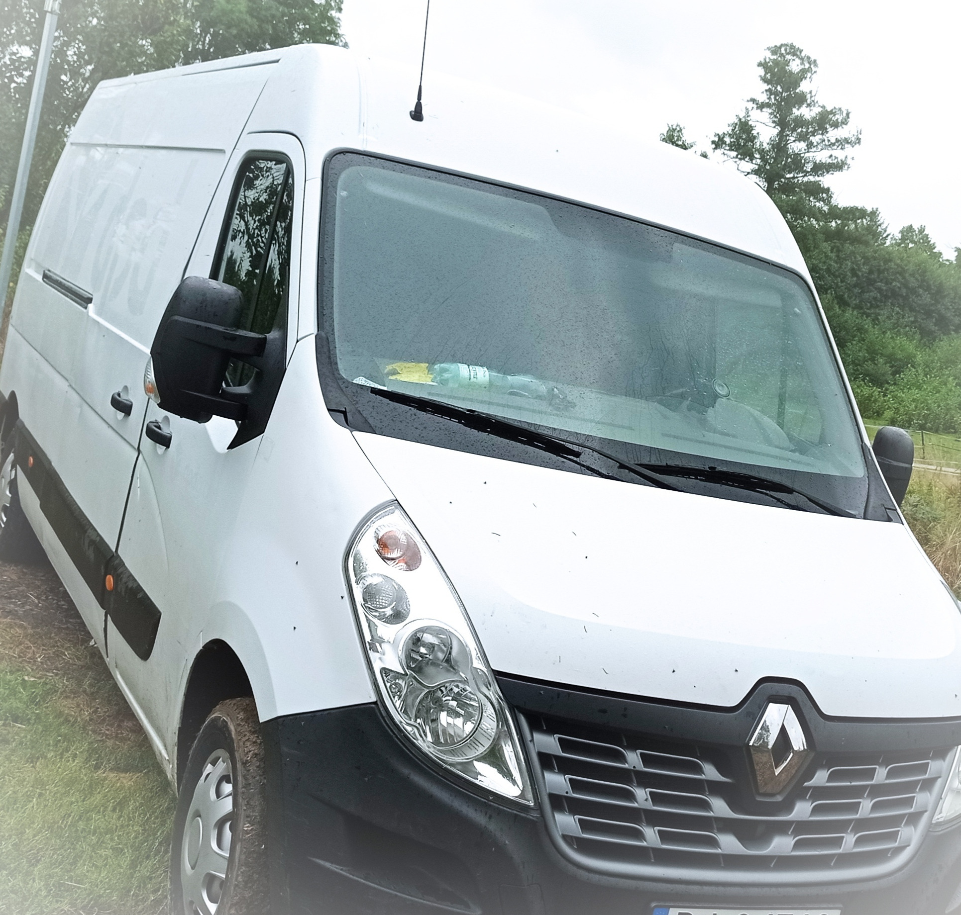 Biały samochód dostawczy Renault Master zaparkowany w Gryfowie Śląskim, widok z przodu pod kątem, na przedniej szybie widoczna butelka z napojem.