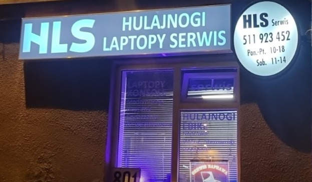 Fasada lokalu HLS z podświetlanymi szyldami: HLS Hulajnogi Laptopy Serwis oraz okrągły szyld z numerem telefonu i godzinami otwarcia.