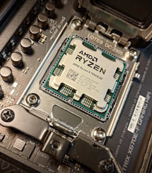 Instalacja procesora AMD Ryzen 7 7950X3D na płycie głównej w Gdańsku, widoczne elementy montażowe i slot RAM.