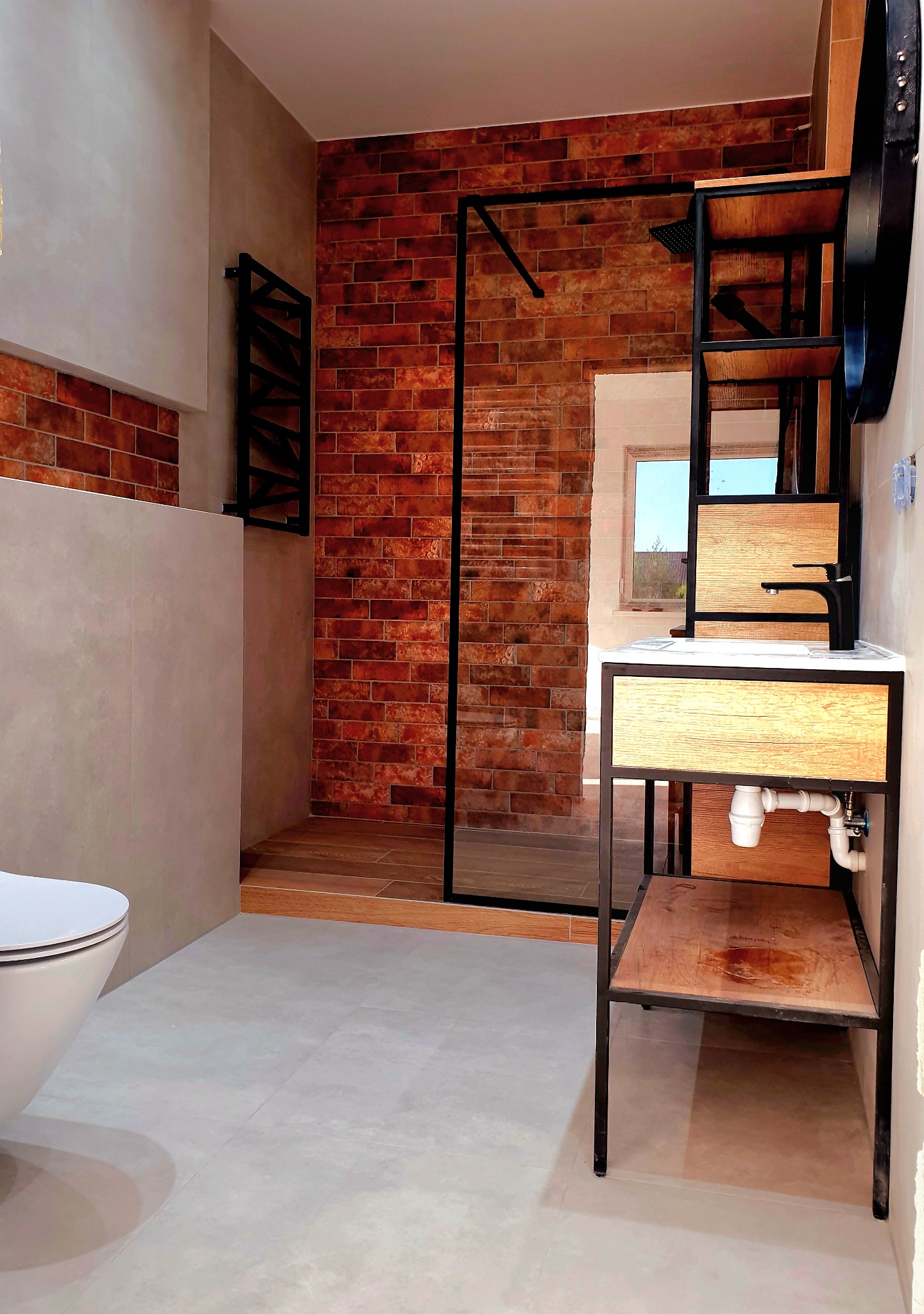 Nowoczesna łazienka z kabiną prysznicową wyłożoną cegłą, umywalką na metalowym stelażu z drewnianymi półkami i wiszącą toaletą.