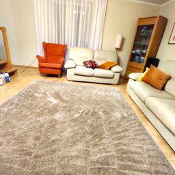 Clinox - Profesjonalne pranie kanap i tapicerki meblowej Warszawa - Beżowy, puszysty dywan w salonie z jasnymi meblami i drewnianą podłogą, widok z perspektywy podłogi.