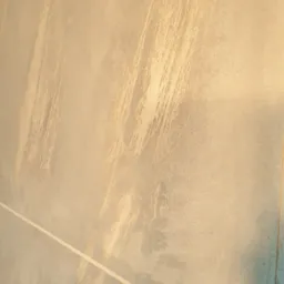 Tekstura ściany z efektem malowania pędzlem w odcieniach beżu i błękitu, z widoczną linią podziału kolorów.