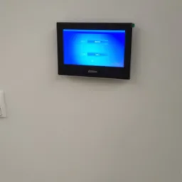 Zamontowany na ścianie panel sterowania wideodomofonu marki Dahua z widocznym menu wyboru języka i regionu.