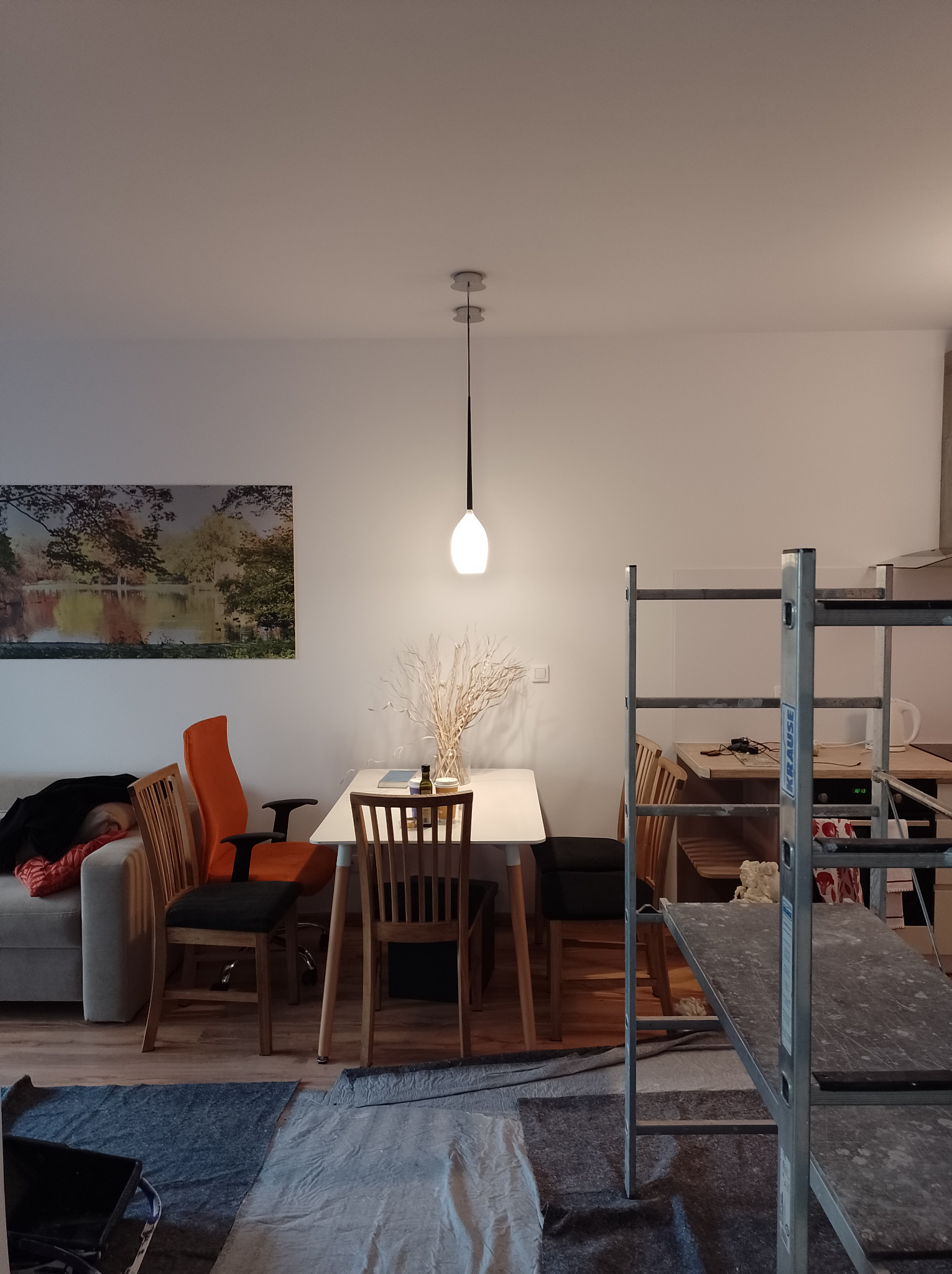 Pokój w trakcie prac: drabina malarska, zabezpieczona podłoga, świeżo pomalowane ściany w tle.