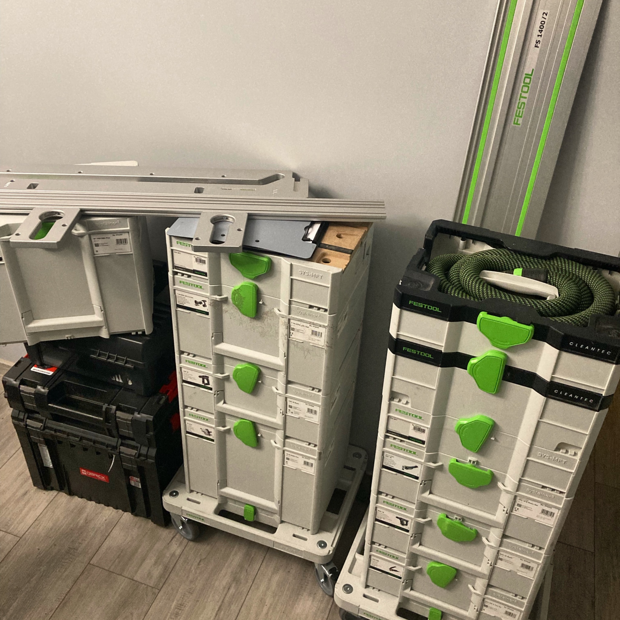 Zestaw skrzynek narzędziowych Festool Systainer różnych typów, ułożonych w stosy na podłodze, obok szyny prowadzącej FS 1400/2.