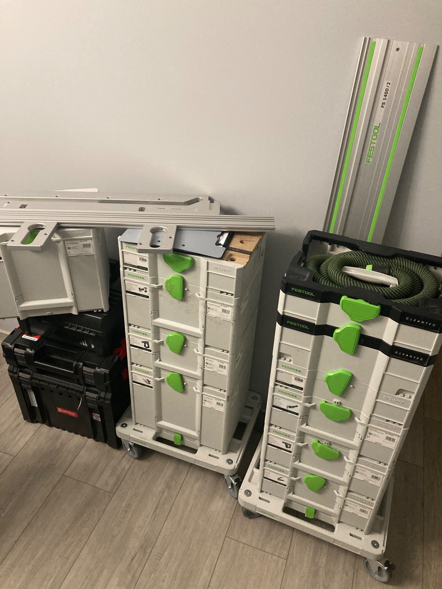 Zestaw skrzynek narzędziowych Festool Systainer z szynami prowadzącymi FS 1400/2, widoczne na podłodze z paneli.