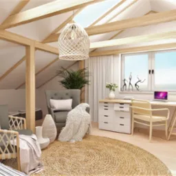 Jasne poddasze zaaranżowane jako pokój dzienny i biuro, z drewnianymi belkami stropowymi, plecionym dywanem i elementami dekoracyjnymi w stylu boho.