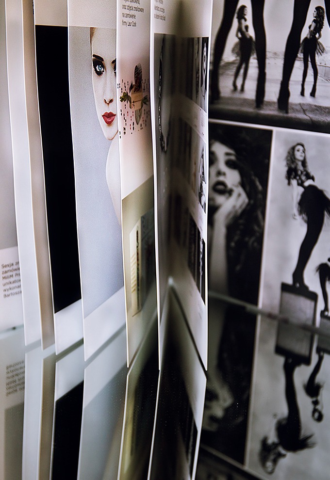 Otwarta książka lub katalog z fotografiami modelek, widoczne zbliżenia portretowe i zdjęcia sylwetek w stylizacjach modowych.