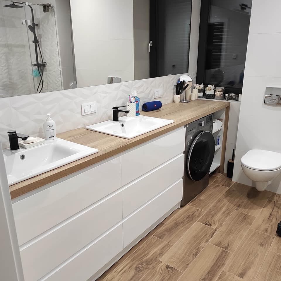 Nowoczesna łazienka z dwiema umywalkami nablatowymi i pralką ukrytą w zabudowie meblowej z białymi frontami i blatem drewnopodobnym.