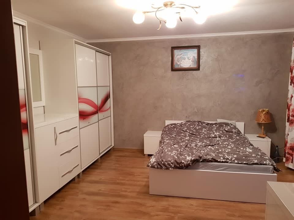 Biała szafa przesuwna z czerwonym motywem w sypialni z szarą ścianą i drewnianą podłogą.