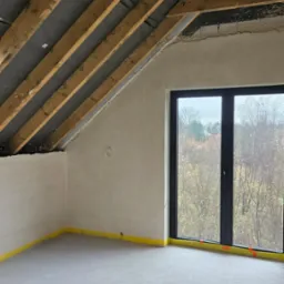 Poddasze w trakcie wykończenia: widoczne drewniane krokwie z izolacją, ściany po nałożeniu gładzi, zabezpieczone żółtą taśmą podłogi i okno z widokiem na drzewa.