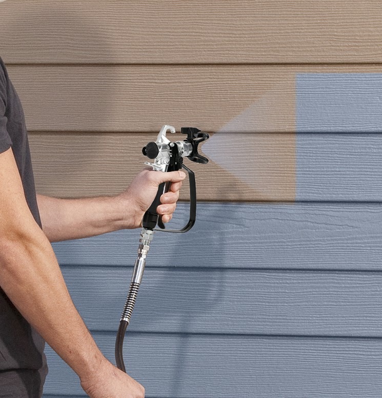 Malowanie desek elewacyjnych pistoletem natryskowym, widoczna różnica kolorów między starą a nową farbą.