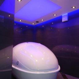 CENTRUM PSYCHOSOMATYKI - Nowoczesna kapsuła sensoryczna w pomieszczeniu z nastrojowym, niebieskim oświetleniem punktowym i kwadratowym panelem sufitowym.