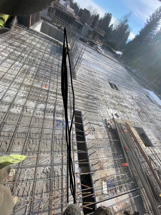 Siatka zbrojeniowa przygotowana do zalania betonem na budowie domu, widok z góry, w tle drzewa i budynki w budowie.